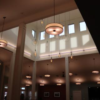 A view of the interior space featuring elegant lighting fixtures and large windows that illuminate the area.