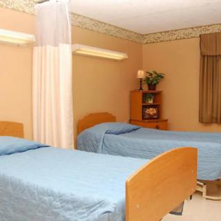 A hospital room with two patient beds equipped with blue linens and a curtain divider.