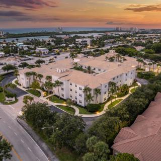 Aerial view of a residential complex surrounded by lush greenery at sunset.