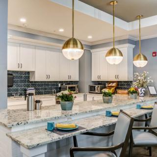 A modern kitchen with pendant lighting, granite countertops, and white cabinets.