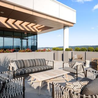 A modern outdoor terrace with comfortable seating and a view of the sky.