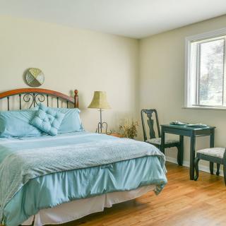 A cozy bedroom with a neatly made bed, soft blue bedding, and classic wooden furniture.