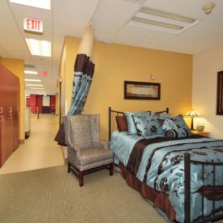 A cozy bedroom setup with a bed, chair, and decorative elements in a hallway setting.