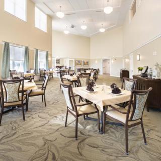 A spacious dining room with elegantly set tables and chairs, featuring large windows and stylish decor.