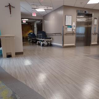 A quiet hospital hallway featuring a waiting area and an elevator.