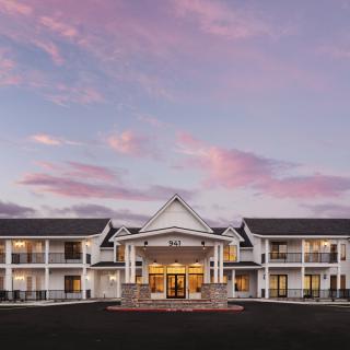 A beautifully lit hotel building with a grand entrance set against a colorful sunset sky.