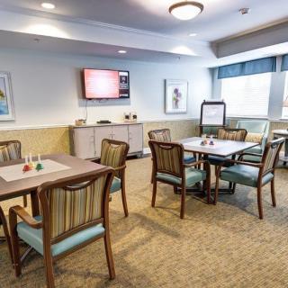 A comfortable room with tables and chairs, a television, and decorative artwork.