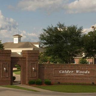 Entrance to a gated community featuring a brick wall and landscaped surroundings.