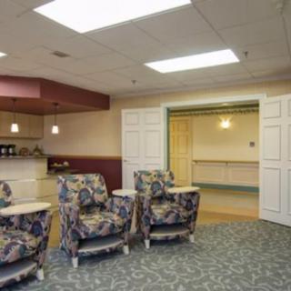 A waiting area with patterned chairs and carpet, illuminated by ceiling lights.