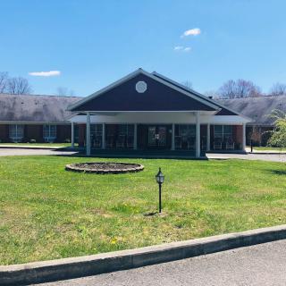 A building with a covered entrance and surrounding lawn under a clear blue sky.