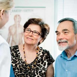A couple in conversation with a healthcare professional during a medical consultation.