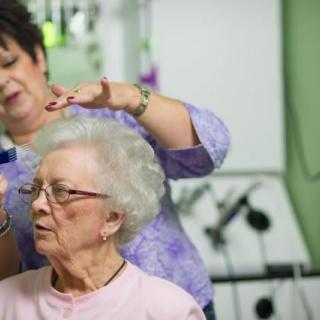An elderly woman getting her hair styled at a salon.