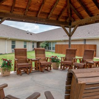A cozy outdoor patio with wooden chairs under a gazebo, perfect for relaxation.