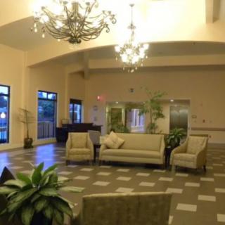 A spacious lobby area featuring elegant chandeliers, comfortable sofas and chairs, and decorative plants.