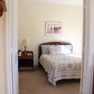 A cozy bedroom with a decorative bedspread and a nightstand with a lamp.