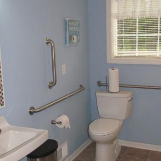A bathroom equipped with grab bars for accessibility alongside a toilet and sink.