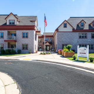 A welcoming entrance to a residential apartment complex with well-maintained landscaping and an American flag.