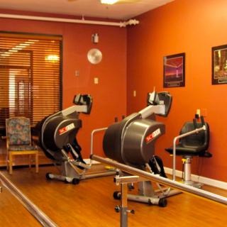 A rehabilitation room equipped with exercise machines and parallel bars for physical therapy.