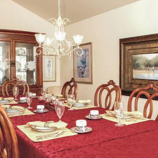An elegantly decorated dining room with a red tablecloth and fine china set for a meal.