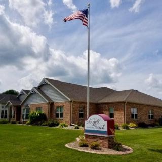 A brick building with a flagpole and sign in front, set against a cloudy sky.