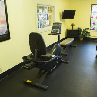 A small gym with a stationary bike and television.