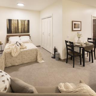 A cozy studio apartment with a combined bedroom, dining area, and living space decorated in neutral tones.