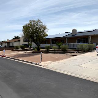 A quiet suburban street lined with single-story houses and a prominent tree in the front yard.