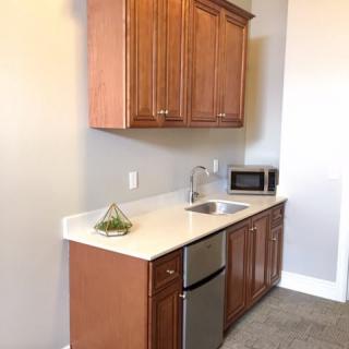 A compact kitchen setup featuring a countertop with cabinets, a sink, and a microwave.