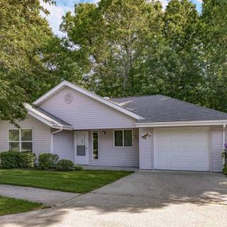 A suburban house with a driveway and attached garage, surrounded by trees.