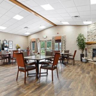 A cozy dining area featuring wooden tables and chairs, a stone fireplace, and elegant decor.