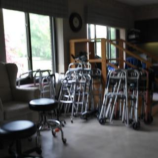 A room filled with walkers and wheelchairs near large windows.