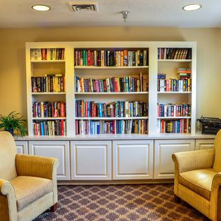 A cozy reading area featuring a large bookshelf filled with books and two comfortable armchairs.