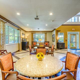 A spacious and well-lit dining area with a round table and wooden chairs, featuring large windows and elegant decor.