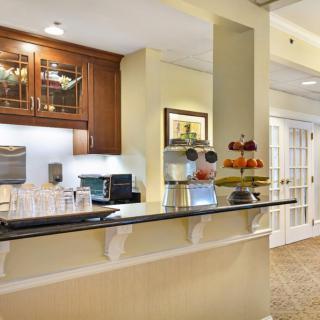 A modern kitchen interior with a counter featuring a coffee maker and fruit display.