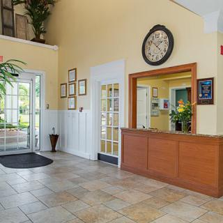A welcoming lobby area featuring a reception desk, large clock, and decorative plants.