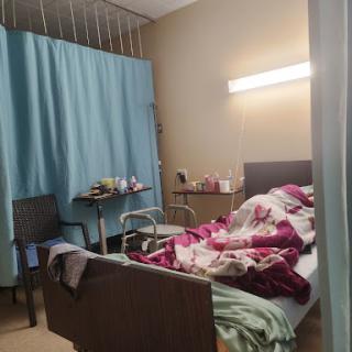 A patient room in a hospital, featuring a bed with blankets and medical equipment.