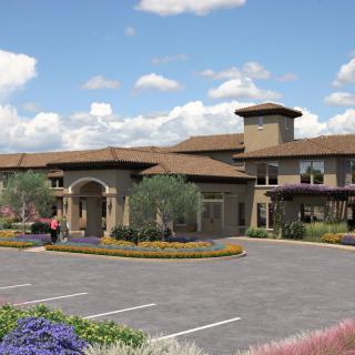 A modern building with neatly landscaped surroundings and a spacious parking lot under a partly cloudy sky.