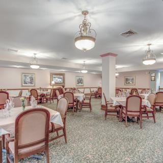 An elegant dining area with neatly arranged tables and chairs, featuring chandeliers for lighting.