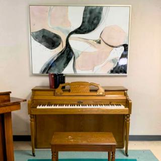 A vintage wooden piano accompanied by an abstract painting, creating a harmonious blend of music and art in the interior.