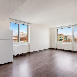 Bright empty apartment with hardwood floors and large windows.