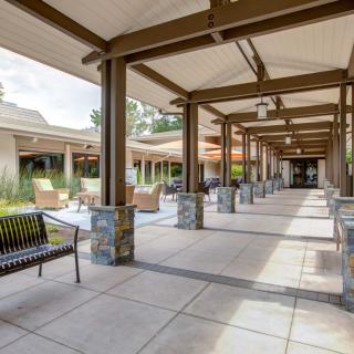 A modern covered walkway with stone columns and benches on either side.