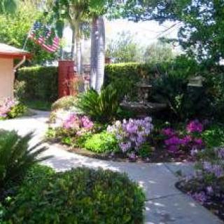 A beautifully landscaped garden features a pathway surrounded by vibrant flowers and lush greenery.