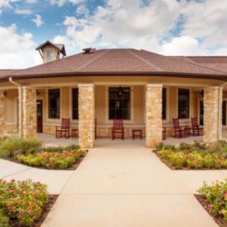 A stone faade house with a welcoming porch and landscaped garden.