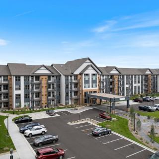 A modern apartment complex with a spacious parking lot in front.
