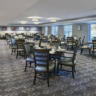 An empty dining room with neatly arranged tables and chairs, featuring modern decor and lighting.