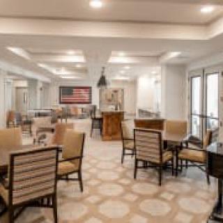 A modern dining area with neatly arranged tables and chairs, featuring elegant lighting and decor.