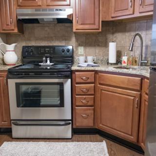 A cozy kitchen featuring wooden cabinets, a stainless steel stove and oven, and a sink with a countertop.
