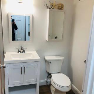 A clean and simple bathroom with a sink, toilet, and mirror cabinet.