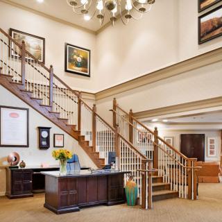 A spacious lobby with a grand wooden staircase and elegant decor.