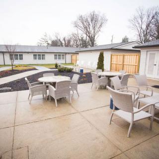 An outdoor patio area with tables and chairs on a cloudy day, surrounded by residential buildings.